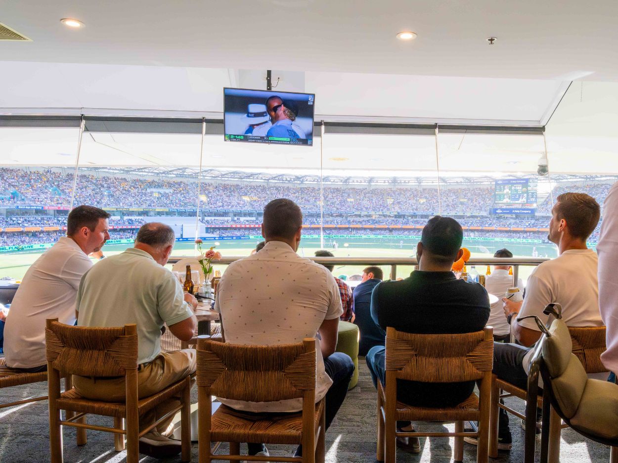 Five patrons looking out of the window watching the cricket at The Gabba